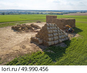 Green field with haystacks and agricultural machine around blue sky on an autumn sunny day.. Large haystacks in a field with agricultural machinery tractor against a blue sky on a sunny day. Стоковое фото, агентство Ingram Publishing / Фотобанк Лори