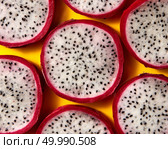 Top view of tropical exotic cut round slices of Dragon fruit or Pitaya on a yellow background. Close-up view.. Close up view of background from round slices of Dragon fruit or Pitaya on a yellow background. Стоковое фото, агентство Ingram Publishing / Фотобанк Лори