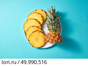 Yellow rings of sliced pineapple with a green top on a white round plate isolated on a blue background with space under the text, top view. round pieces of pineapple on a white plate on a blue background. Стоковое фото, агентство Ingram Publishing / Фотобанк Лори