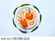 A creative pattern of vegetables - kinds of paprika peppers in the center of the whole and pieces and green chili along the circle of the composition. Food concept . Top view.. Yellow paprika pepper whole and slices in the center of the composition and green chili pepper in a circle of a white plate on a white background. Flat lay. Стоковое фото, агентство Ingram Publishing / Фотобанк Лори