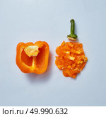 Finely chopped half a pepper with a stem and half a pepper with seeds on a gray background. Top view. Food concept. Fresh half pepper and finely chopped orange pepper on a gray background. Стоковое фото, агентство Ingram Publishing / Фотобанк Лори