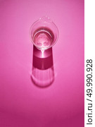 Long shadows and reflex from water glass on a pink background with copy space. Top view.. Clean glass with water on a pink paper background with shadows. Стоковое фото, агентство Ingram Publishing / Фотобанк Лори