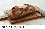 Rye oval bread on a cutting board with a knife on a white background. Fresh rye bread with knife. Стоковое фото, агентство Ingram Publishing / Фотобанк Лори