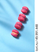 Colored pink macaroons lined in a row on a blue background. Place for text. Top view. Mini cake macaron on light blue background pastel colors, top view. Стоковое фото, агентство Ingram Publishing / Фотобанк Лори