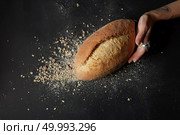 hand in flour holds a fresh bread against the flakes on dark background. hands with a bread. Стоковое фото, агентство Ingram Publishing / Фотобанк Лори