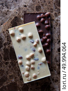 black and white chocolate bars with whole hazelnuts on a marble background. black and white chocolate bars. Стоковое фото, агентство Ingram Publishing / Фотобанк Лори