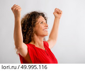 Portrait of a happy middle aged brunette with arms up expressing victory. Стоковое фото, агентство Ingram Publishing / Фотобанк Лори