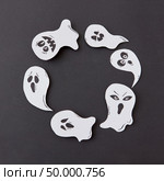 Greeting card, creative application with handmade paper terrible spirits smiling and laughing ghosts on a black background, copy space. Flat lay. Happy Halloween. Handcraft round frame of flying floating singing smiling specters on a black background. Стоковое фото, агентство Ingram Publishing / Фотобанк Лори