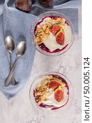 Figs pudding parfait with yogurt, blueberry jam, figs, hazelnut, and cookies in glass on white marble background. Flatlay top view. Стоковое фото, агентство Ingram Publishing / Фотобанк Лори