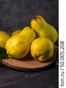 Ripe yellow quinces or queen apple fruits and sliced quince halves with seeds in craft cork plates on black rustic background. Стоковое фото, агентство Ingram Publishing / Фотобанк Лори