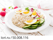 Oatmeal porridge with boiled egg and vegetable salad with fresh radish, cucumber and lettuce. Healthy dietary breakfast. Стоковое фото, агентство Ingram Publishing / Фотобанк Лори