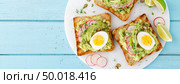 Toasts with avocado guacamole, fresh radish, boiled egg, chia and pumpkin seeds. Diet breakfast. Delicious and healthy plant-based food. Flat lay. Top view. Banner. Стоковое фото, агентство Ingram Publishing / Фотобанк Лори