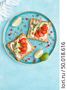 Toasts with feta cheese, tomatoes, avocado, pomegranate, pumpkin seeds and flaxseed sprouts. Diet breakfast. Delicious and healthy food. Flat lay. Top view. Стоковое фото, агентство Ingram Publishing / Фотобанк Лори