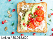 Toasts with feta cheese, tomatoes, avocado, pomegranate, pumpkin seeds and flaxseed sprouts. Diet breakfast. Delicious and healthy food. Flat lay. Top view. Стоковое фото, агентство Ingram Publishing / Фотобанк Лори