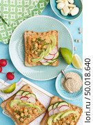 Toasts with chickpea hummus, avocado, fresh radish, cucumber, sesame seeds and flaxseed sprouts. Diet breakfast. Delicious and healthy plant-based vegetarian, vegan food. Flat lay. Top view. Стоковое фото, агентство Ingram Publishing / Фотобанк Лори