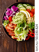 Buddha bowl dish. Healthy balanced lunch with quinoa, grilled chicken meat, lettuce salad, pepper, cucumber, tomato and avocado guacamole with lemon. Стоковое фото, агентство Ingram Publishing / Фотобанк Лори