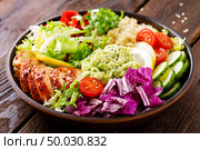 Buddha bowl dish. Healthy balanced lunch with quinoa, grilled chicken meat, lettuce salad, pepper, cucumber, tomato and avocado guacamole with lemon. Стоковое фото, агентство Ingram Publishing / Фотобанк Лори