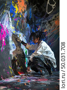 A young artist is kneeling on the ground, focused on adding colorful strokes to an abstract canvas in a studio. Стоковое AI-изображение, AI-художник Данила Большаков / Фотобанк Лори
