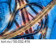 Aerial view of road in the modern city at night in winter. Top view of traffic in highway with city illumination. Cars on elevated road and interchange overpass. Busy intersection. Expressway at dusk. Стоковое фото, агентство Ingram Publishing / Фотобанк Лори
