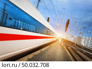 High speed white passenger train on tracks in motion at sunset. Commuter train. Railway station. Railroad with vintage toning. Travel background. Train. Стоковое фото, агентство Ingram Publishing / Фотобанк Лори