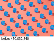 Diagonal rows pattern from transparent blue plastic ice cubes on a background in a trend color of the year 2019 Living Coral Pantone.. Creative pattern with blue light ice cubes with shadows on a background in a color of the year 2019 Living Coral Pantone. Стоковое фото, агентство Ingram Publishing / Фотобанк Лори