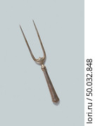 Metall retro fork for meat isolated on a white background, place for text.. Vintage meat fork isolated on a white background, copy space. Стоковое фото, агентство Ingram Publishing / Фотобанк Лори
