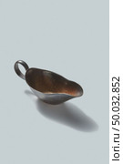 Vintage retro metall empty gravy boat for sauce on a white background with shadows, place for text.. Retro bronze sauceboat with shadows on a white background. Vintage kitchenware. Стоковое фото, агентство Ingram Publishing / Фотобанк Лори