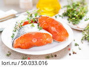 Fresh raw salmon fish steaks on white kitchen background. Стоковое фото, агентство Ingram Publishing / Фотобанк Лори