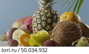 Ripe pineapple with fresh natural exotic fruits on a wooden table on a blue background. Vertical panoramic motion 4K UHD video, 3840, 2160p. Concept of vegetarian diet eating.. Vertical panoramic upward slow motion with composition from fresh natural exotic fruits on a wooden table on a blue background. Motion, 4K UHD video, 3840, 2160p. Стоковое фото, агентство Ingram Publishing / Фотобанк Лори