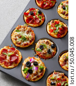 Bite-sized mini pizzas with various toppings in baking tray. Стоковое AI-изображение, AI-художник Olga Didraga / Фотобанк Лори