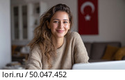 Молодая женщина изучает турецкий язык онлайн с преподавателем на ноутбуке дома, демонстрируя современное цифровое образование и дистанционное изучение иностранного языка. Стоковое AI-изображение, AI-художник Катерина Бондарец / Фотобанк Лори