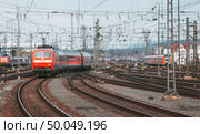 Railway station with modern red commuter train  in motion in the evening in Nuremberg, Germany. Red train on the railroad track with vintage toning. Стоковое фото, агентство Ingram Publishing / Фотобанк Лори
