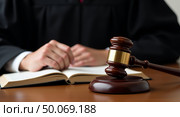 Closeup of judges hands on legal text with gavel in courtroom setting. Стоковое AI-изображение, AI-художник Андрей Бакусов / Фотобанк Лори