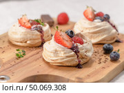 Small pavlova cakes with fresh raspberries and blueberries. Стоковое фото, агентство Ingram Publishing / Фотобанк Лори