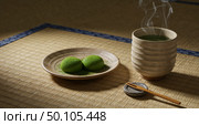 Matcha Moment: a cup of steaming matcha tea and two wagashi on a rustic plate sit in the calming light, an inviting scene of traditional Japanese culinary serenity. Стоковое AI-изображение, AI-художник Лариса Пономарева / Фотобанк Лори