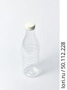 Plastic transparent empty bottle for dairy products, water and other liquid with white cup on a light gray background, mock up. Copy space.. Transparent empty bottle for liquid on a light background. Mock up. Стоковое фото, агентство Ingram Publishing / Фотобанк Лори