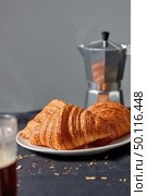 Italian coffee maker with morning hot aromatic beverage and homemade freshly baked french pastry on dark textile background. Place fo rtext. Continental breakfast.. Coffee maker with homemade croissant on a gray background. Стоковое фото, агентство Ingram Publishing / Фотобанк Лори