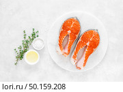 Fresh salmon steaks with ingredients for cooking on white board, view from above. Стоковое фото, агентство Ingram Publishing / Фотобанк Лори