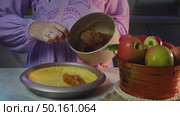 Pouring homemade apple sauce onto plate beside fresh apples in cozy kitchen setting. Стоковое видео, видеограф Zakharova Natasha / Фотобанк Лори