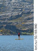 Stand up paddleboarding on lake. Watersport on lake. Tourist outdoor activity at Lagoa Comprida, Serra da Estrela National Park in Portugal. Стоковое фото, агентство Ingram Publishing / Фотобанк Лори