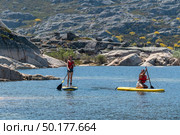 Stand up paddleboarding on lake. Watersport on lake. Tourist outdoor activity at Lagoa Comprida, Serra da Estrela National Park in Portugal. Стоковое фото, агентство Ingram Publishing / Фотобанк Лори