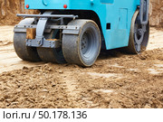 Construction site features a blue roller compacting earth on a freshly excavated ground during daylight hours. Стоковое фото, фотограф Виктория Тельминова / Фотобанк Лори