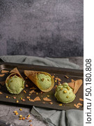 Balls of pistachio ice cream in waffle cones on a dark background. Стоковое фото, агентство Ingram Publishing / Фотобанк Лори