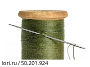 Old Single wooden spool of thread olive green color and needle closeup white background. Стоковое фото, фотограф Camptoloma / Фотобанк Лори