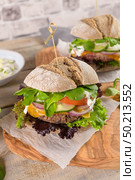 Healthy vegan burger with fresh vegetables and yogurt sauce on rustic kitchen counter top. Стоковое фото, агентство Ingram Publishing / Фотобанк Лори