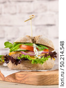 Healthy vegan burger with fresh vegetables and yogurt sauce on rustic kitchen counter top. Стоковое фото, агентство Ingram Publishing / Фотобанк Лори