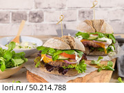 Healthy vegan burger with fresh vegetables and yogurt sauce on rustic kitchen counter top. Стоковое фото, агентство Ingram Publishing / Фотобанк Лори