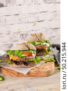 Healthy vegan burger with fresh vegetables and yogurt sauce on rustic kitchen counter top. Стоковое фото, агентство Ingram Publishing / Фотобанк Лори