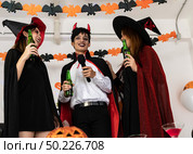 Group of young adult and teenager people celebrating a Halloween party carnival Festival in Halloween costumes drinking alcohol beer singing a song and dancing. Стоковое фото, агентство Ingram Publishing / Фотобанк Лори
