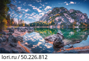 Beautiful Braies lake at sunrise in autumn in Dolomites, Italy. Landscape with mountains, blue sky with clouds, water with reflection, stones, trees with colorful leaves. Lake in fall. Panorama. Beautiful Braies lake at sunrise in autumn in Dolomites, Italy. Стоковое фото, агентство Ingram Publishing / Фотобанк Лори